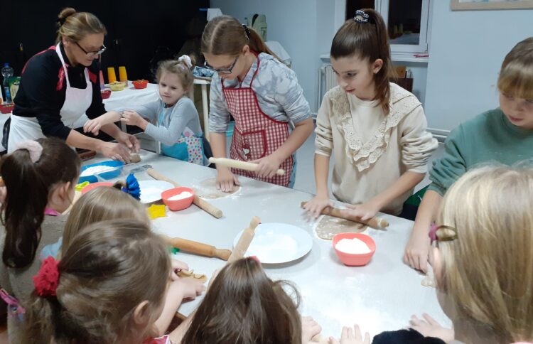 Malí spolkári za pomoci vedúcej Miliny Častvenovej rozvaľkujú medovníkové cesto