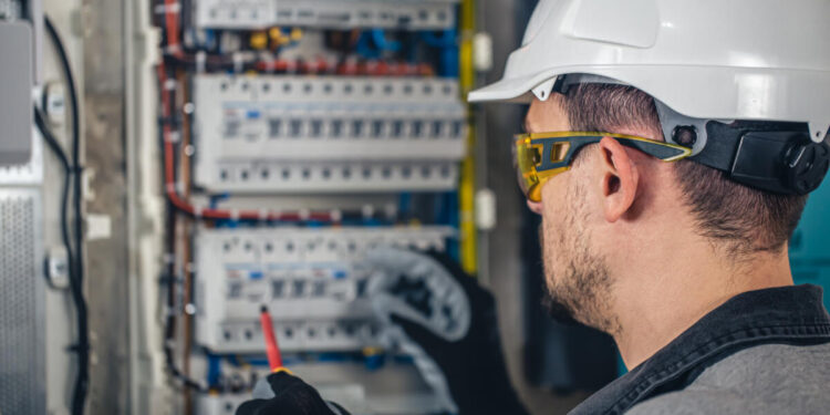 Man, an electrical technician working in a switchboard with fuses. Installation and connection of electrical equipment.