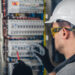 Man, an electrical technician working in a switchboard with fuses. Installation and connection of electrical equipment.